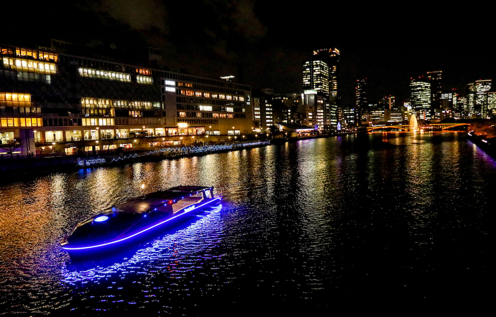 An illuminated electric cruise boat on Osaka's waterways at night